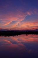 orangefarbene Wolken reflektieren klares blaues Wasser foto