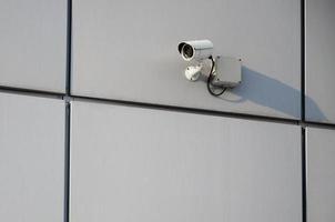 Weiße Überwachungskamera, eingebaut in die Metallwand des Bürogebäudes foto