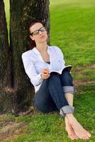 junge Frau, die ein Buch im Park liest foto