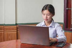 ein studentenmädchen mit weißem hemd studentenanzug tippt und lernt online vom laptop im haus, mit notebook und w-lan auf dem schreibtisch. bildungs- und studienkonzept, kopierraumaufnahme foto