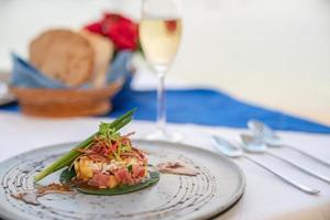 Teller mit Thunfischsalat am Esstisch mit Champagner zum Abendessen im Restaurant. foto