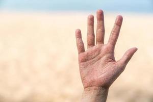 hände befleckt mit sand, strand und meer hintergrund. foto