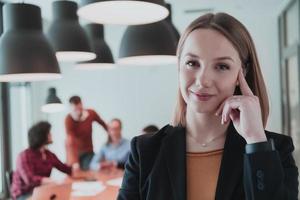 Porträt eines glücklichen Geschäftsfraubesitzers im modernen Büro. Geschäftsfrau lächelt und blickt in die Kamera. beschäftigtes vielfältiges team, das im hintergrund arbeitet. Führungskonzept. Kopfschuss. foto