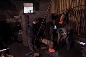 Schmiedearbeiter mit mechanischem Hammer in der Werkstatt foto
