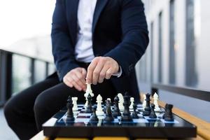 Nahaufnahmefoto der Hände des Geschäftsmannes, die sich auf einem Schachbrett bewegen, männlicher Geschäftsmann, der Schach spielt foto