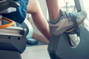 junger Mann mit einem Heimtrainer in einem Indoor-Fitnesscenter foto