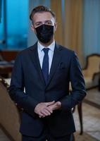 geschäftsmann, der im büro eine schützende gesichtsmaske trägt foto