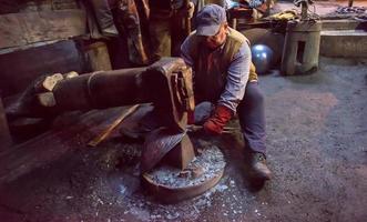 Schmiedearbeiter mit mechanischem Hammer in der Werkstatt foto