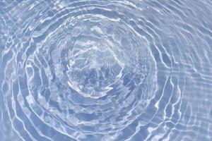 defocus verschwommene, transparente, blaue, klare, ruhige wasseroberflächenstruktur mit spritzer, blase. glänzender blauer wasserkräuselungshintergrund. Wasseroberfläche im Schwimmbad. blaues Blasenwasser scheint. foto