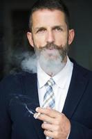 Porträt des Geschäftsmannes, der eine Zigarette raucht foto
