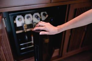 Frauenhand offen, Flaschen Wein im Kühlschrank lagernd. Kühlen und Konservieren von Wein. foto