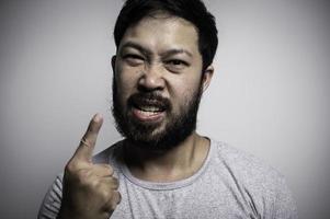 Porträt des asiatischen jungen Mannes auf weißem Hintergrund, Konzept des wütenden Mannes foto