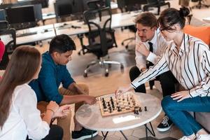 multiethnische gruppe von geschäftsleuten, die schach spielen, während sie eine pause im entspannungsbereich eines modernen startbüros machen foto