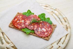 Salami-Sandwich auf Holzbrett und Holzhintergrund foto