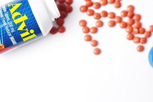 washington, usa - oktober 02 2022 flaschen advil und pillen auf einem weißen tisch verteilt. fieber, schmerzmittel, beliebtes amerikanisches schmerzmittel, ibuprofen. foto