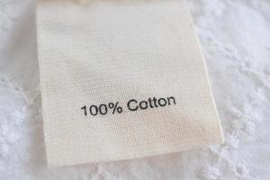 Kleidungsetikett auf Baumwollstoff Textur Hintergrund foto