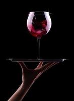Glas Rotwein auf einem schwarzen foto