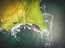 dramatische Luftaufnahme von oben nach unten malerische grüne Klippen mit landwirtschaftlichen Feldern über dem Ozean mit malerischer Küstenlinie auf der Küstenroute des wilden Atlantikwegs foto