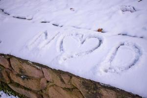 buchstaben und herz geschrieben auf den schnee des waldes foto