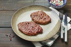 zwei gegrillte Ribeye-Steaks, Gewürze und Tomaten-Gurken-Salat mit Sauerrahm foto