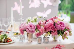 schöner heller Blumenstrauß der Pfingstrose auf dem Hochzeitstisch foto