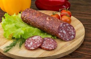 Salami auf Holzbrett und Holzhintergrund foto