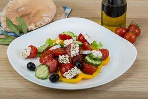 griechischer Salat auf dem Teller und Holzhintergrund foto