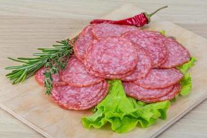 geschnittene Salami auf Holzbrett und Holzhintergrund foto