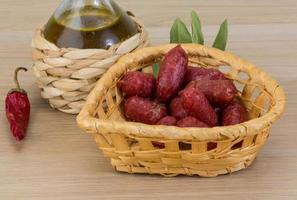 Mini-Salami in einem Korb auf Holzhintergrund foto