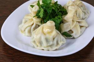 khinkali auf dem teller und dem hölzernen hintergrund foto