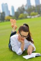 junge Frau, die ein Buch im Park liest foto