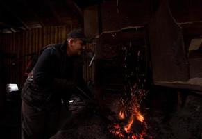 junger traditioneller schmied, der mit offenem feuer arbeitet foto