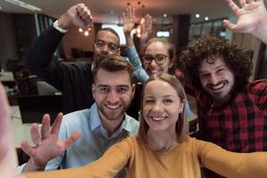 Gruppe von Geschäftsleuten während der Pause von der Arbeit, die ein Selfie-Foto machen, während sie die Freizeit im Entspannungsbereich eines modernen Großraum-Startup-Büros genießen. selektiver Fokus foto