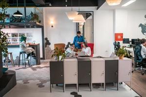 Gruppe lässiger multiethnischer Geschäftsleute, die eine Pause von der Arbeit machen und verschiedene Dinge tun, während sie ihre Freizeit im Entspannungsbereich eines modernen Großraum-Startup-Büros genießen foto