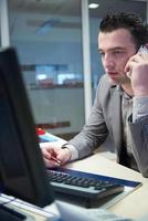 Geschäftsmann, der per Telefon im Büro spricht foto