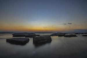 Langzeitbelichtungsfotografie von Wellen und Kieselsteinen am Strand bei Sonnenuntergang foto