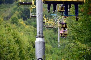 Menschen fahren mit einer Seilbahn. die beine der passagiere hängen über dem bergwald foto