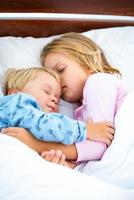 kleines Mädchen und Junge schlafen auf weißem Bett