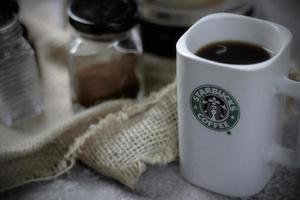 washington - usa september, 26 2022 starbucks kaffeetasse auf grauem tisch mit kaffeeflasche und kaffeemühle. foto