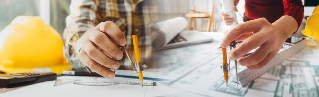 Zwei Kollegen diskutieren über Datenverarbeitung und Tablet, Laptop mit einem Architekturprojekt auf der Baustelle am Schreibtisch im Büro foto