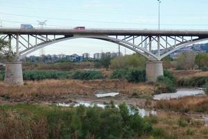 moderne Brücke über einen Fluss, über den große Fahrzeuge und Touristen fahren. foto