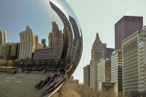 chicago, il, usa - 22. märz 2018 - reflektiert die gebäude auf der cloud gate statue im millenium park, central city, mit einigen touristen, die herumlaufen foto