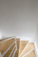 Die moderne geschwungene Holztreppe mit dem weißen Metallhandlauf. foto