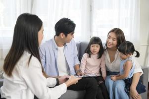 asiatisches familientreffen mit weiblichen immobilienmaklern oder versicherungsberatern, die förderungen, hypotheken, darlehen, eigentum und medizinisches krankenversicherungskonzept anbieten. foto