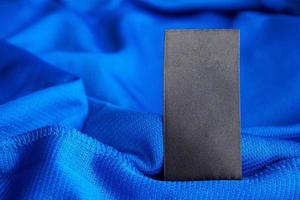 schwarzes leeres Wäschepflegeetikett auf blauem Jersey-Polyester-Sporthemdhintergrund foto