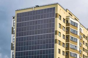 Sonnenkollektoren an der Wand eines mehrstöckigen Gebäudes auf Sturmwolkenhintergrund. erneuerbare Sonnenenergie. ein energieeffizientes Haus, das die Energie von Erde, Sonne, Luft und Abwasser nutzt foto