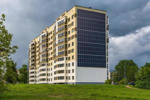 Sonnenkollektoren an der Wand eines mehrstöckigen Gebäudes auf Sturmwolkenhintergrund. erneuerbare Sonnenenergie. ein energieeffizientes Haus, das die Energie von Erde, Sonne, Luft und Abwasser nutzt foto