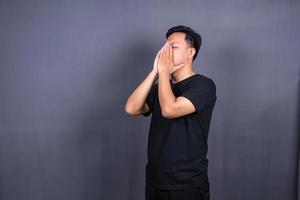 Trauriger Mann mit den Händen auf dem Gesicht in Traurigkeit, isoliert auf grauem Hintergrund, Copyspace foto