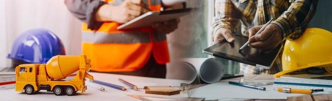 Zwei Kollegen diskutieren über Datenverarbeitung und Tablet, Laptop mit einem Architekturprojekt auf der Baustelle am Schreibtisch im Büro foto