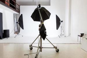 leeres fotostudio mit beleuchtungsausrüstung. fotografenarbeitsplatzinnenraum mit professioneller werkzeugsatzausrüstung. Blitzlicht-weiße Hintergrundszenen bereit für Studioaufnahmen. modernes Fotografenstudio foto